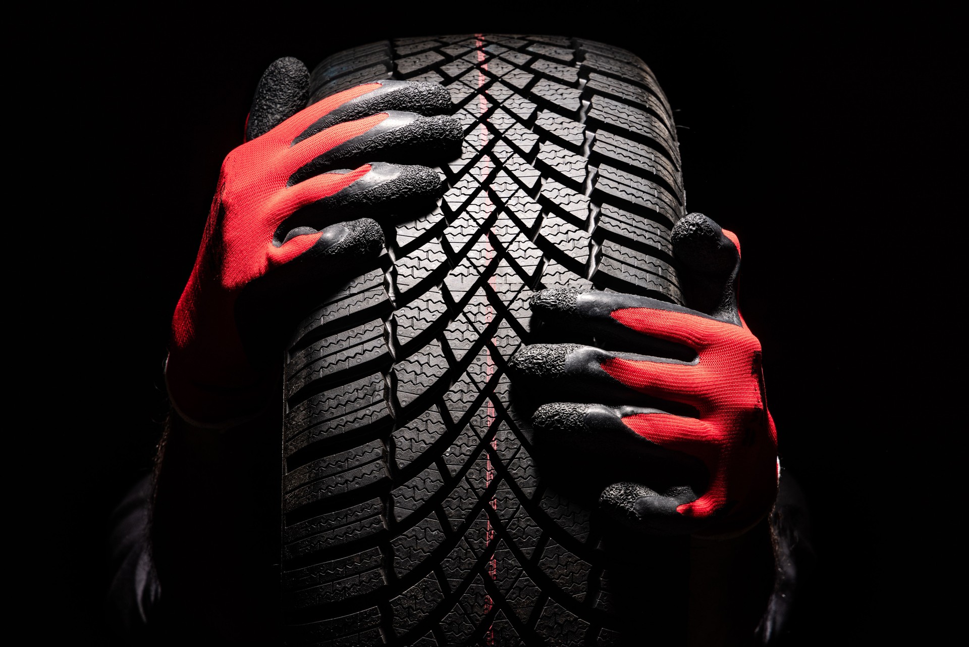 Car tire service and hands of mechanic holding new tyre on black background with copy space for text